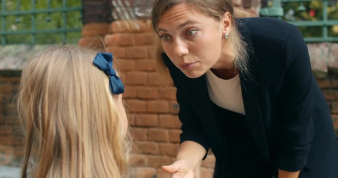 Close up view of mother child conflict. Young angry woman yelling at her schoolgirl daughter for getting bad grades or unpropriate behaviour at street. Concept of parenthood.