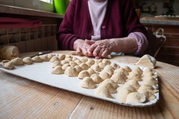 an elderly woman prepares handmade orecchiette, an excellent dish from southern Italy. orecchiette in the foreground and an old woman's hands blurred in the background