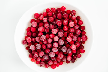 Frozen cranberries in the white plate.Fresh red berry cranberries.White background.Top view.Close up