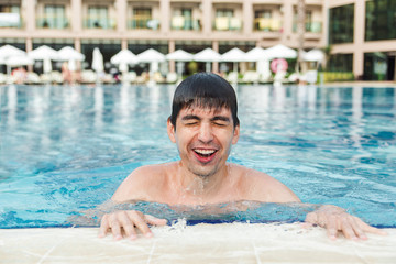 Young smilling handsome man in swimming pool.Summer and healthy lifestyle concept