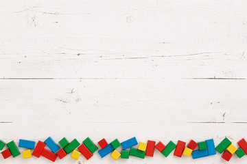 Top view on colorful wooden toy blocks on a white background wooden table.