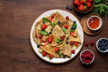 Thin crepes decorated with fresh berries and mint leaves. Traditional Russian, Ukrainian or French pancakes