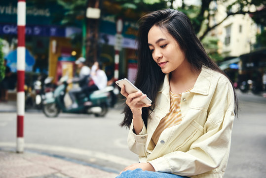 Vietnamese woman using smartphone on the street