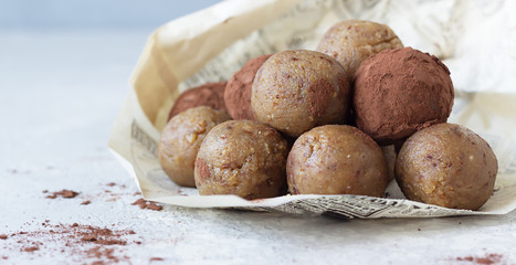 Healthy vegetarian energy balls with chickpea, peanut butter, raisin and cocoa powder. Homemade paleo truffles. Light grey background, selective focus. 