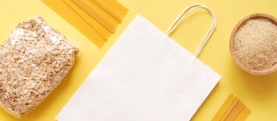 Dry goods, stockpiling, food supplies for staying home concept, delivery, donation, volunteer. pasta, oatmeal, rice, shopping bag mockup on yellow background, copyspace, mockup