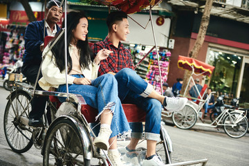 Fototapeta na wymiar Wide shot of couple traveling by Vietnamese pedicab