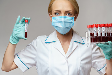 medical doctor nurse woman wearing protective mask and gloves - holding rack with virus blood tests