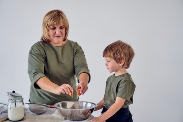 boy with his grandmother knead the dough on a light background