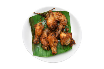 Herbal fried chicken on banana leaves in white dish on white background