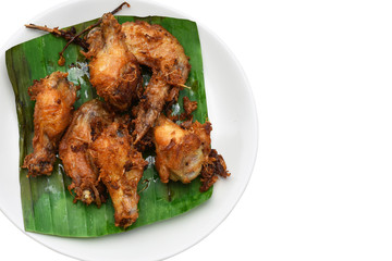 Herbal fried chicken on banana leaves in white dish on white background