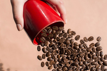 young woman holding a red cup full of coffee beans, coffee beans flying out from a cup