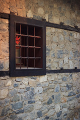 Old stone house which has stone wall and wooden window with grid