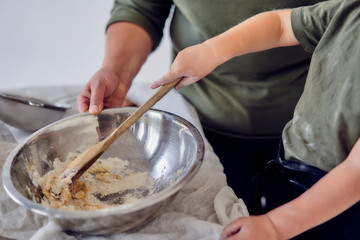 Fototapeta premium boy with his grandmother knead the dough on a light background