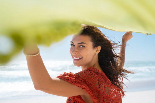 Smiling Woman Holding Green Scarf At Beach