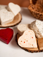 Hard, young cheese with spices in the shape of hearts, love for dairy products, a lot of cheeses, on a stump of derava, natural product, close-up