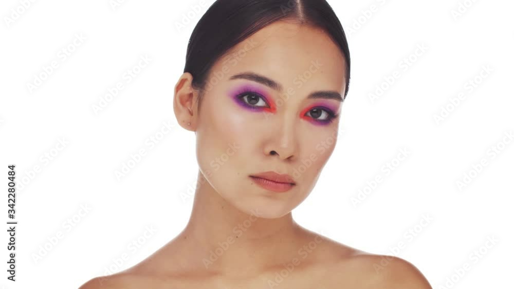 Sticker A calm half naked asian woman with bright fashion eye makeup is posing and looking to the camera isolated over white background in studio