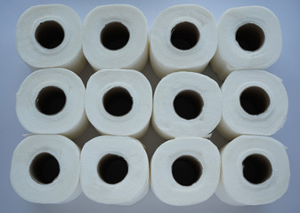 A dozen of toilet rolls are stacked on white background.  During Corona virus, Covid 19 pandemic,  people stock up tissues for their sanitary household. 
