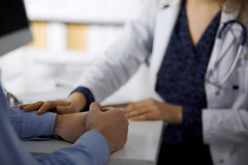 Obraz premium Female doctor and male patient discussing current health examination while sitting in clinic, close-up. Medicine concept