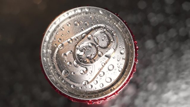 Red can rotate on table with drops of water wet background. Top down view of metal can unopened. bottle in small drops of water.