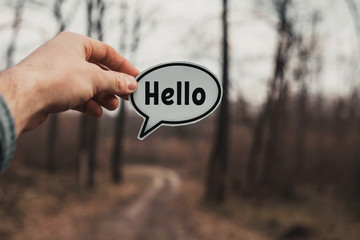 male hand holds a tablet with the word hello. to the forest