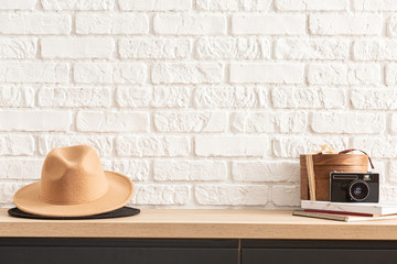 wooden shelf with retro photo camera and hat. Stylish interior of living room with white brick wall, brown box, elegant accessories. Minimalistic concept of home decor. Template. - 342283413