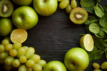 Mixed green fruits and vegetables placed on black wooden table