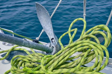 Close up Bow of the sail boat with anchor and light green rope. Sailing at summer sunny day. Yachting concept and sea background