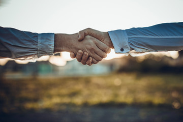 Business handshake and business people concepts. Two men shaking hands on sunset background.
