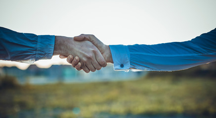Business handshake and business people concepts. Two men shaking hands on sunset background.