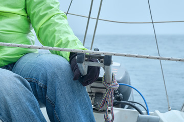 Man driving a sailing boat in the blue sea outdoors on a summer foggy day. Yachting concept and sea...