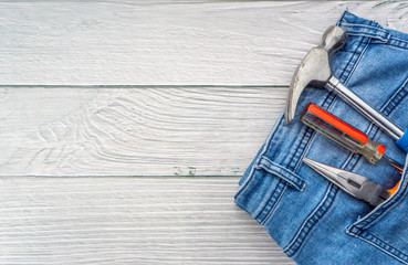 Jeans, screwdriver, hammer and pliers on wooden background. Jeans texture, Blue denim jeans with...