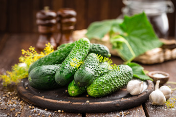 Fermenting cucumbers, cooking recipe salted or marinated pickles with garlic and dill with ingredients on kitchen wooden rustic background