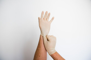 Close up von Händen die sich medizinische Latexhandschuhe anziehen als Schutz vor Viren wie dem Coronavirus Covid-19 