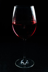 Transparent glass glass with a red alcoholic drink. Red wine in a glass on a black background