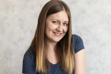 Portrait of beautiful young smiling girl. Close up of usual woman with cute smile. Brown hair or a fair Russian happy girl wearing casual dark blue t-shirt