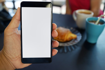 Cropped shot view of man hand holding a smartphone in the cafe with blank copy space screen for text message or information content