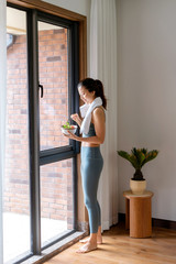 A young Asian woman eating healthy food after indoor exercise