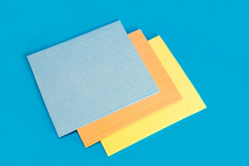 Three rectangular multi-colored napkins on a blue background. The concept of cleanliness in the house, wet cleaning. Household. Close-up, top view, selective focus.