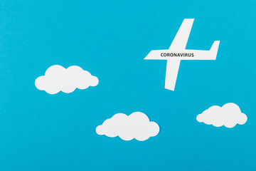 Paper airplane and text about Coronavirus on blue paper background. Traveling during the COVID-19 pandemic.