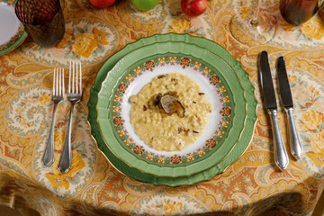 porridge with truffles, table setting in a plate with knives, forks and glass. top view
