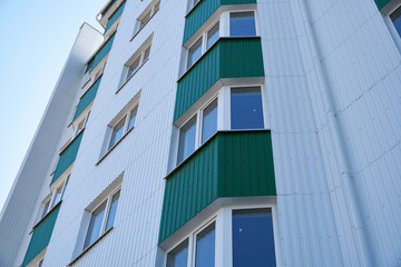 Obraz premium facade of a new multi-storey building with white and green metal siding, many Windows