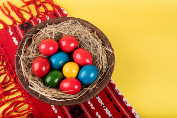 Wicker basket of colorful Easter eggs isolated on yellow