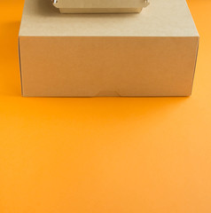 a paper box for food delivery lies on an orange paper background, space for text