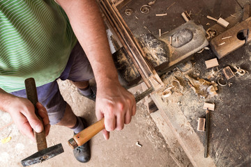 Male carpenter working on old wood in a retro vintage workshop.