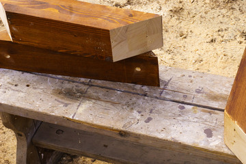 Painting a wooden element with brown paint. Hands in working gloves hold a wooden product and a brush.