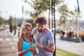 Modern couple making pause on the sidewalk during jogging / exercise.