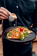 
Belgian waffles with greens, red tomato and orange sauce on a black plate