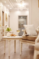 A glass of white wine, crispy croissants and a vase of white flowers sit on the table in the cozy living room