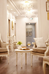 An open vintage book, a glass of white wine and crunchy pastries sit on a vintage table in the bright, cozy living room