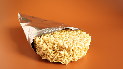 Raw dried instant noodles in open condition from an unnamed foil packaging without a name close-up...